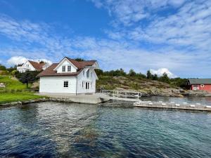 a white house on a dock in the water at Holiday home MOSTERHAMN VI in Mosterhamn