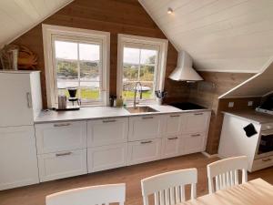 a kitchen with white cabinets and a sink and two windows at Holiday home MOSTERHAMN VI in Mosterhamn