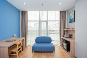 Habitación con silla azul, escritorio y ventana. en Future Shangju Hotel en Shanghái