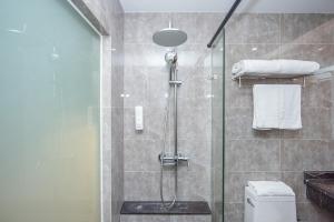 a bathroom with a glass shower with a toilet at Future Shangju Hotel in Shanghai