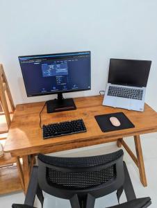 escritorio con monitor de ordenador y ordenador portátil en Mini tropical home with office, en Krambitan