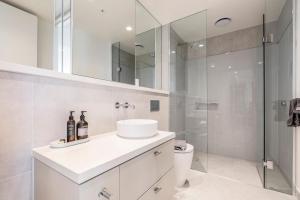 a white bathroom with a sink and a shower at Moonee Valley Park with parking in Melbourne