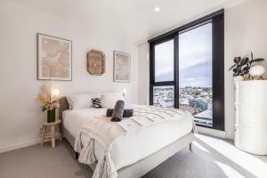 a bedroom with a white bed and a large window at Moonee Valley Park with parking in Melbourne