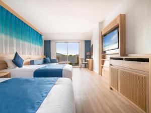 Habitación de hotel con 2 camas y TV de pantalla plana. en Resort Hotel Kume Island, en Kumejima