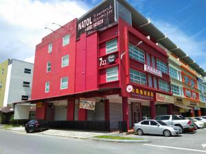 un edificio rojo con coches estacionados en un estacionamiento en Gateway To Kota Samarahan education hub Sama Jaya ind centre classic 30BR by Natol Traveller & Business Inn, en Kuching