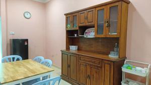 a kitchen with a wooden cabinet and a table and chairs at Casa Indera in Kampung Bota Kiri