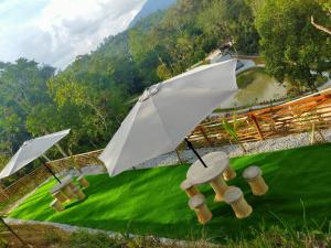 峇冬加里的住宿－The Hillock @ Hulu Tamu，两把白色的伞,坐在绿色的田野上