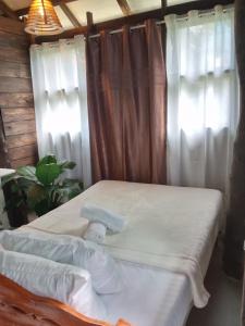 een bed in een kamer met witte gordijnen bij Bird Friendly Inn in Bayawan