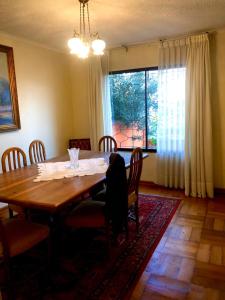 einen Esstisch mit Stühlen und ein großes Fenster in der Unterkunft Casa del Limón in Valparaíso