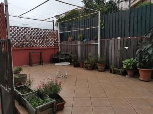 eine Terrasse mit Topfpflanzen, einem Tisch und einem Zaun in der Unterkunft Casa del Limón in Valparaíso