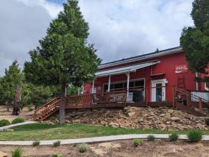 a red building with a porch and a tree at Red Barn Retreat in North Fork