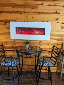 Red Barn Retreat في North Fork: طاولة زجاجية مع كرسيين ومدفأة