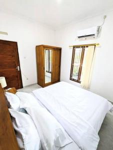 Schlafzimmer mit einem Bett mit weißer Bettwäsche und einem Fenster in der Unterkunft Tropical oasis private home in Krambitan
