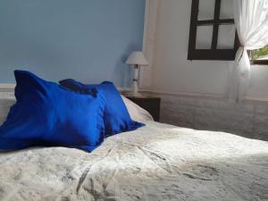 Una cama con almohadas azules encima. en cabaña alma dorada en Huerta Grande