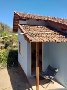 a chair sitting under a roof next to a building at Cantinho da Paz in Miguel Pereira