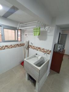 a white bathroom with a sink and a tv at Apartamento Central in Ibagué