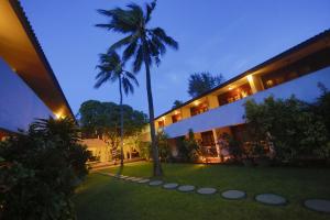 a palm tree in front of a building with a yard at Catamaran Beach Hotel in Negombo