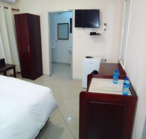 1 dormitorio con 1 cama, escritorio y TV en Kandjo's Bed and Breakfast, en Palapye