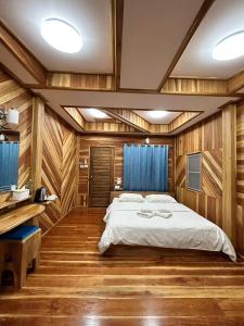 a bedroom with a bed in a room with wooden walls at MAGMAI HOMESTAY & TOWER in Tak