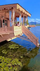 Maharajas palace houseboat في سريناغار: امرأة جالسة على جسر فوق قطعة ماء