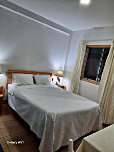 a bedroom with a white bed with a window at Wayra Hospedaje in Cajamarca