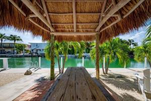 un banco de madera bajo una sombrilla de paja en una playa en Relaxing 2 2 Get Away in the Lower Keys! home, en Summerland Key