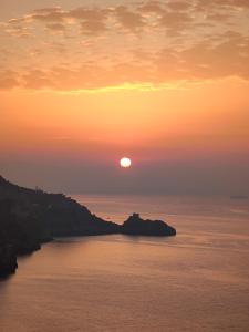 una puesta de sol sobre un cuerpo de agua con la puesta de sol en HOLIDAY double en Praiano
