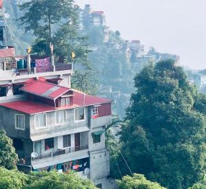 un edificio con techo rojo en la cima de una colina en WARUHANG HOMESTAY en Darjeeling