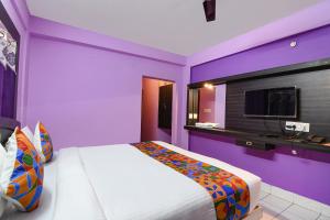 Dieses lila Zimmer verfügt über ein Bett und einen TV. in der Unterkunft FabHotel Bollywood 2.0 in Puri