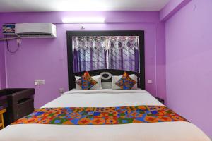 een slaapkamer met een bed met paarse muren en een raam bij FabHotel Bollywood 2.0 in Puri