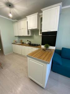 a kitchen with white cabinets and a blue couch at Nur 5 in Uralsk