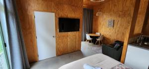 a room with a bed and a television and a table at Beautiful Rural Oasis in Upper Hutt