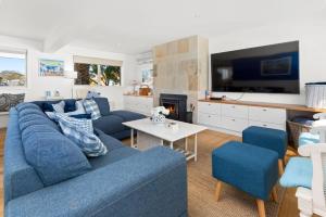 uma sala de estar com um sofá azul e uma televisão em SANTORINI BEACH HOUSE SAFETY BEACH em Safety Beach