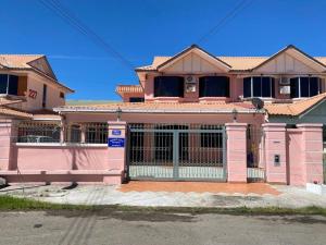 a pink house with a gate in front of it at Indah Jaya Homestay in Sandakan