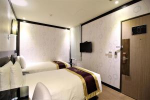 een hotelkamer met 2 bedden en een deur bij J-HOTEL in Kaohsiung