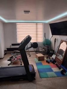 a room with a gym with a treadmill and a television at Departamento moderno y amoblado in Quito