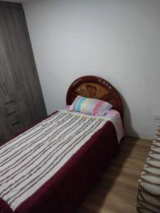 a bed with a wooden headboard in a bedroom at Departamento moderno y amoblado in Quito
