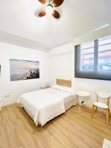a white bedroom with a bed and a ceiling fan at Suites Puente de Hierro in Benicàssim