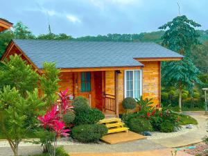 a small log cabin with a porch and flowers at Soundless Resort in Khao Kho