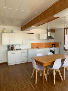 a kitchen with a wooden table and white cabinets at Le Nid in Éclaron