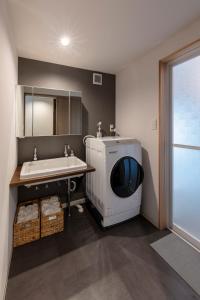 a bathroom with a sink and a washing machine at 奥阿賀七名庵　らくら in Aga