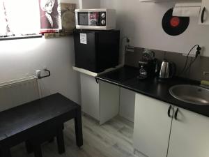 a small kitchen with a sink and a microwave on a refrigerator at studio black and white in Łódź