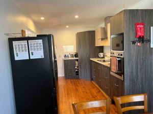 a kitchen with a black refrigerator and wooden floors at Chillin at Adaminaby FSC home in Adaminaby in Adaminaby