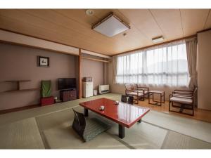 a living room with a table and chairs and a television at Kouunsou in Nasushiobara