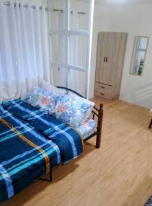 een slaapkamer met een bed met een blauwe deken bij Cozy Condo in Davao City