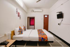 ein Hotelzimmer mit einem Bett und einem TV in der Unterkunft FabHotel Saubhagya Inn in Nashik