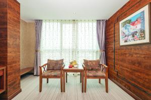een kamer met 2 stoelen, een tafel en een raam bij Xiamen Xiangzun Hotel - Huijing Plaza Branch in Xiamen