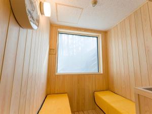 um pequeno quarto com um banco amarelo e uma janela em Rakuten STAY VILLA Fuji Kawaguchiko Forest 2LDK with sauna and terrace em Fujikawaguchiko