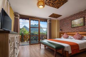 a bedroom with a bed and a large window at Yangshuo Coco Garden Hotel in Yangshuo