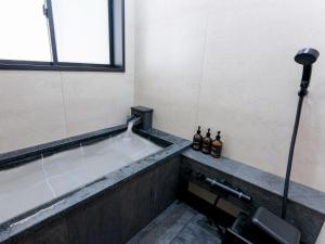 a bathroom with a bath tub with bottles of alcohol at Rakuten STAY VILLA Fuji Kawaguchiko Forest 2LDK with sauna and terrace-Pet Friendly- in Fujikawaguchiko